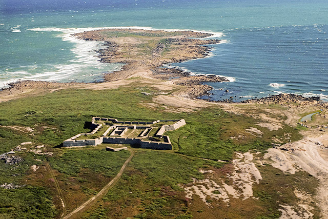 A star-shaped fort near a large body of water seen from above.