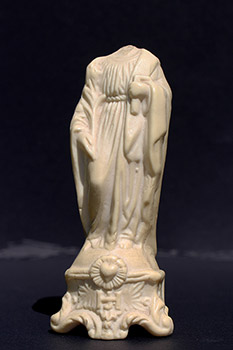 Statuette blanche brisée de saint Joseph. Statuette sans tête; le personnage porte une équerre de charpentier dans sa main gauche.