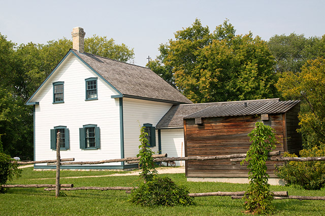 A two-story white building with a black cross affixed to its roof.
