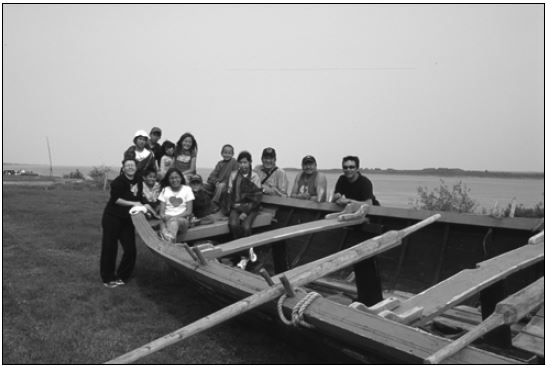 A group of 12 people pose by a York boat.