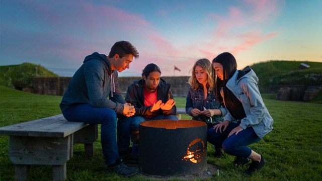 A group of friends sitting around a bonfire inside the fort.
