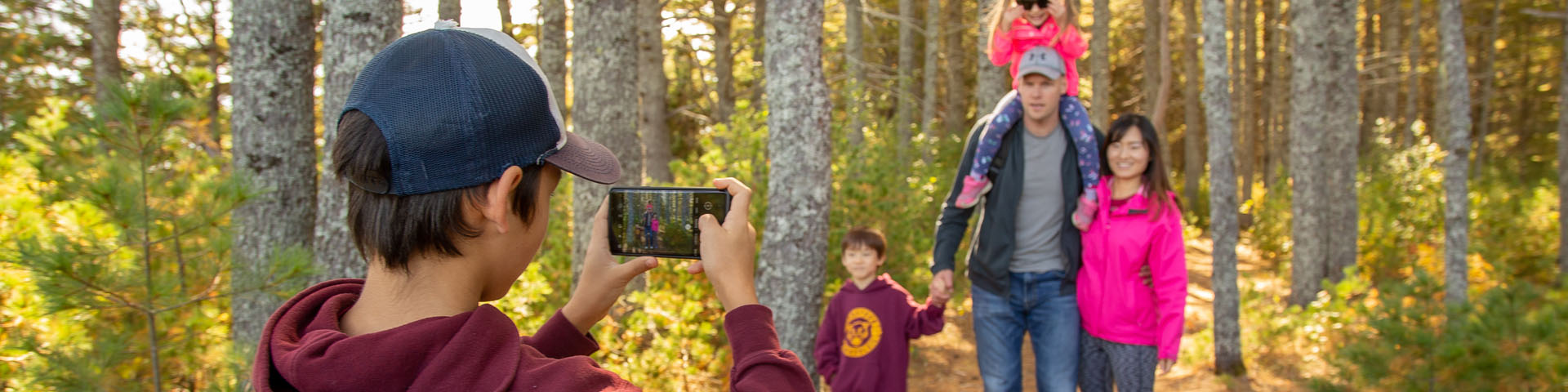 A boy takes a picture of his family on a trail on the island.