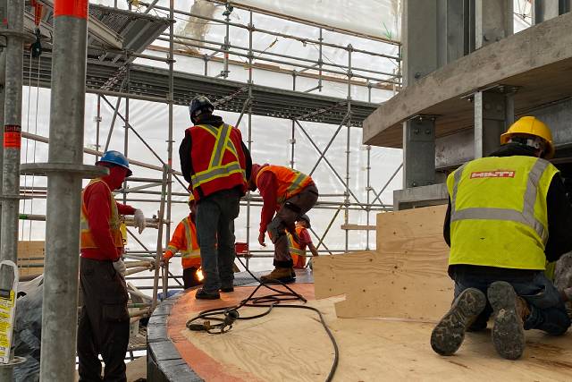 Workers installing a waterproof membrane onto the command post roof.