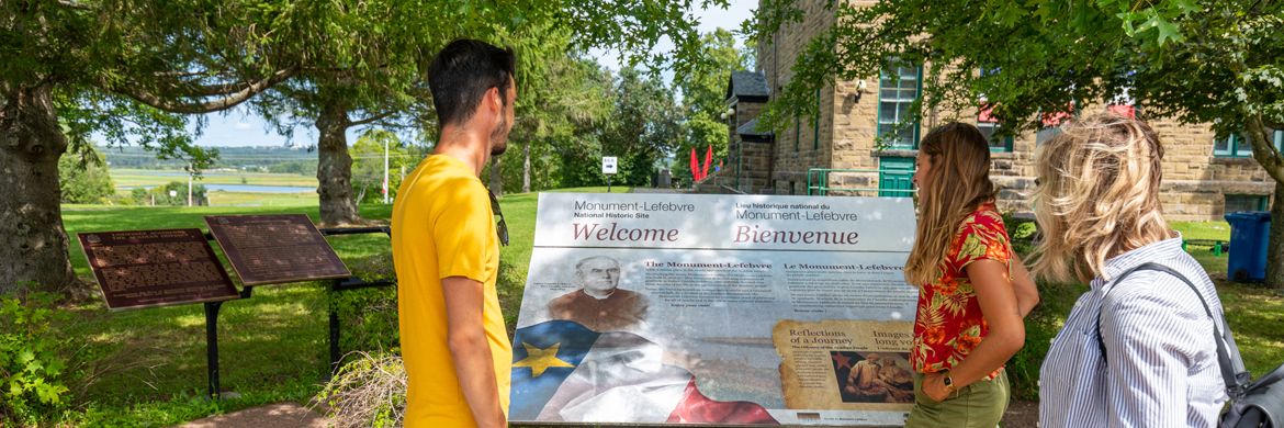 Des visiteurs regardent un panneau à l'extérieur du bâtiment