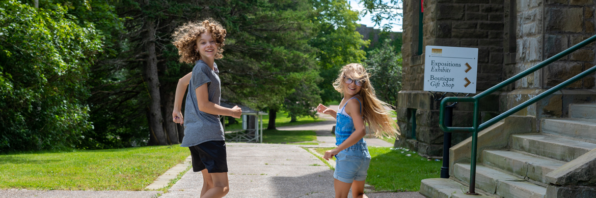 Two children are outside the building, running towards the entrance