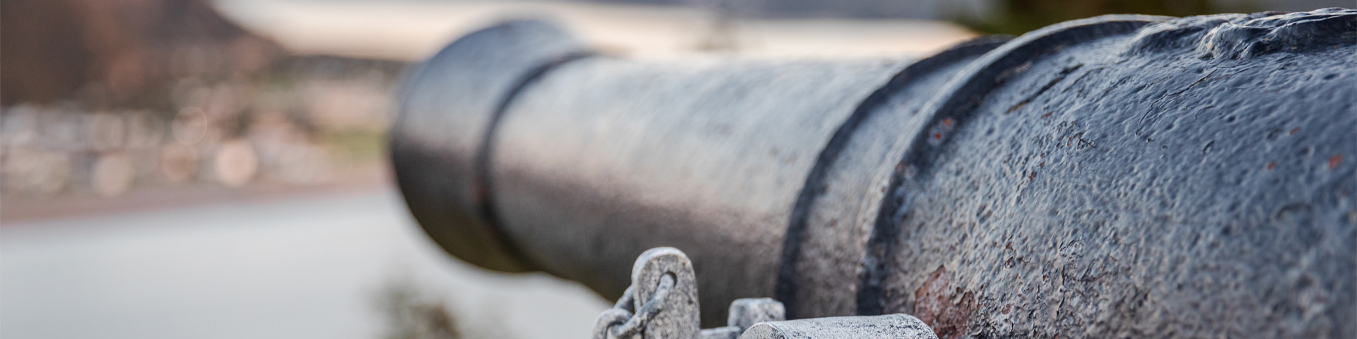 close-up of a cannon overlooking a coastal town