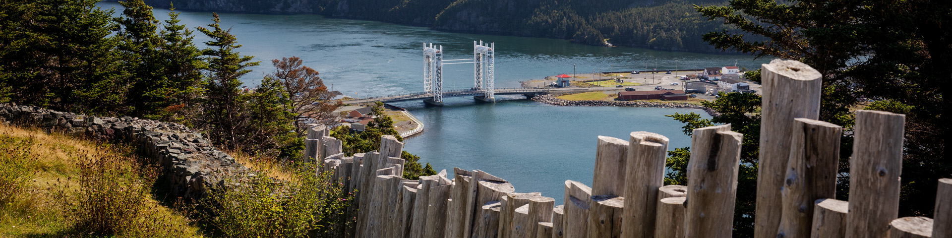 gros plan d'une clôture en bois donnant sur une vue de l'océan avec un grand pont