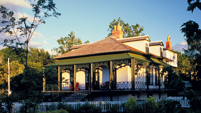 a white house with a green veranda in the sunlight