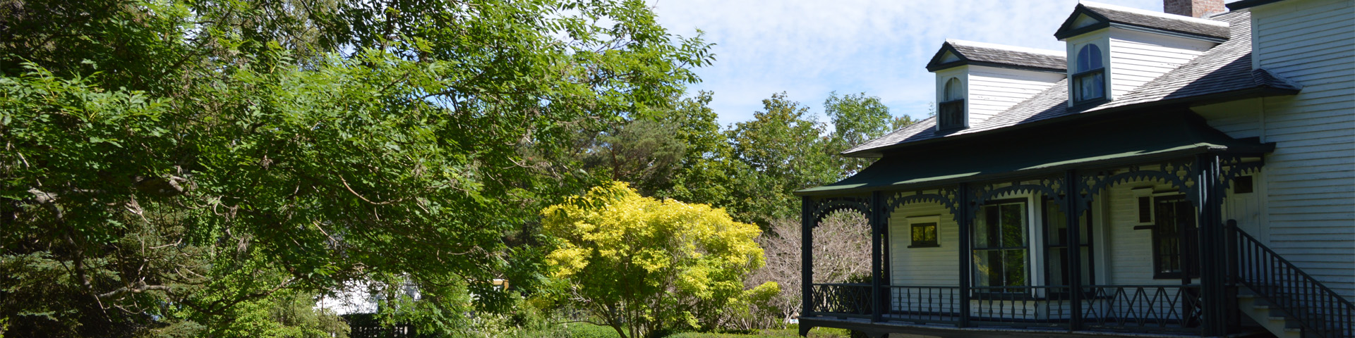 a white house with a green veranda overlooking a green garden