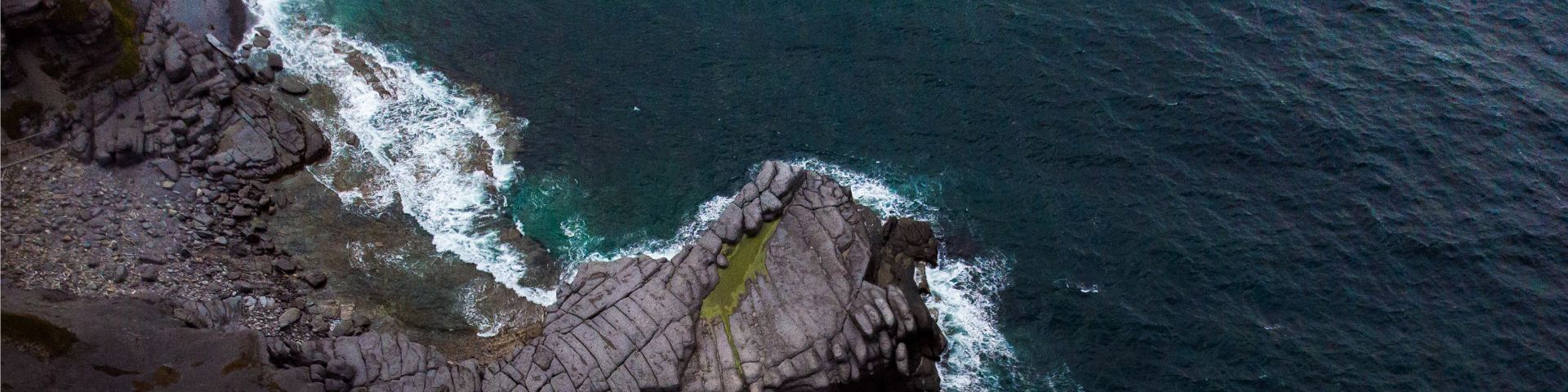 A view from above shows waves splashing on the coast near Port au Choix National Historic Site