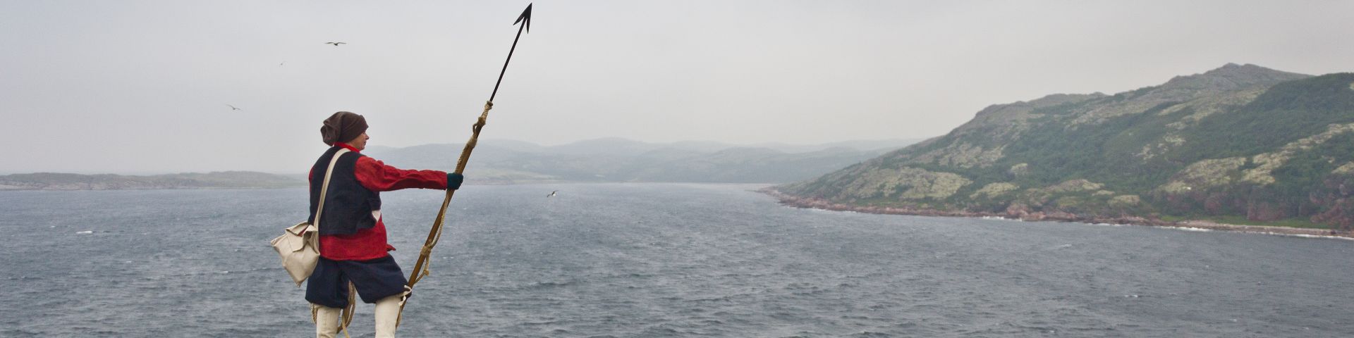 A Parks Canada interpreter in Basque costume stands on the coast near Red Bay National Historic Site