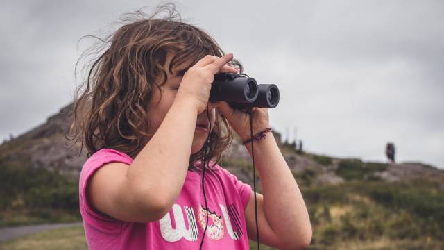 a child holding binoculars up to her face to look through