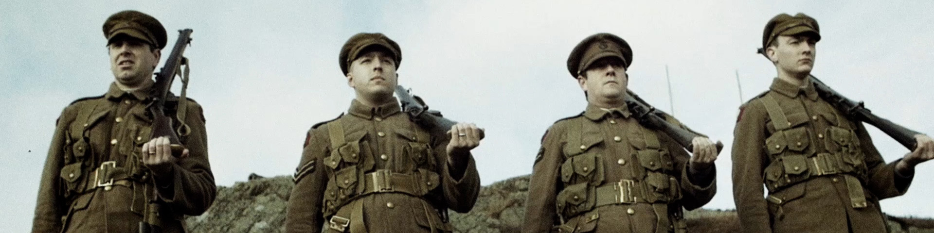 four men in historic military uniform, standing at attention with their guns over their shoulders