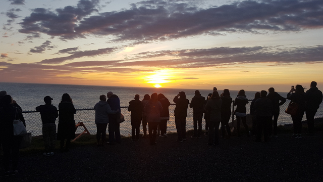a group of people in silhouette watching the sunrise over the ocean 