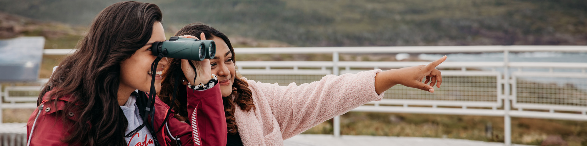 one person pointing something out to another person with binoculars