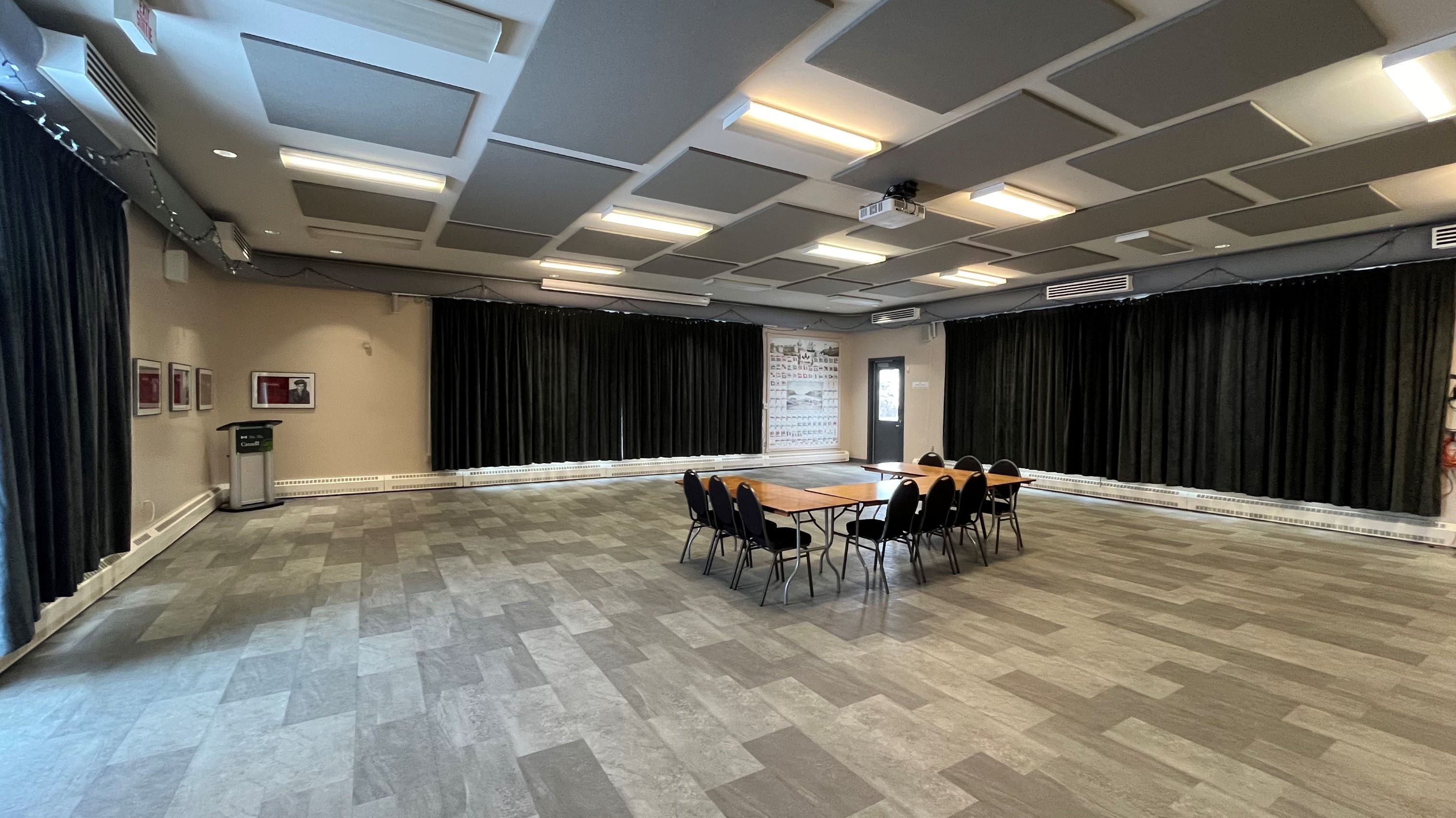 An event room with chairs surrounding a table in the middle of the room and two closed curtains.
