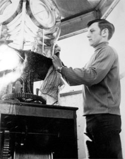 image en noir et blanc d'un homme nettoyant un mécanisme d'éclairage