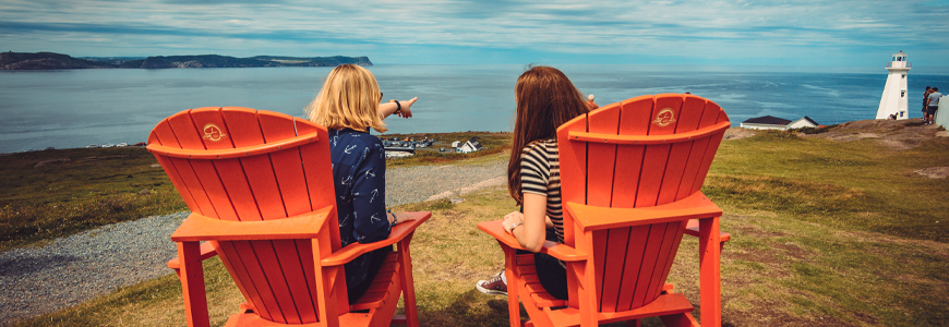 deux individus assis dans des chaises rouges avec vue sur l'océan et un phare