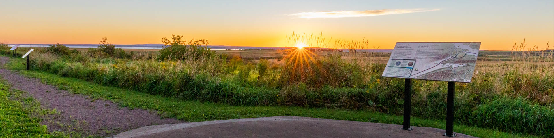 An interpretation panel near a large field at sunset.