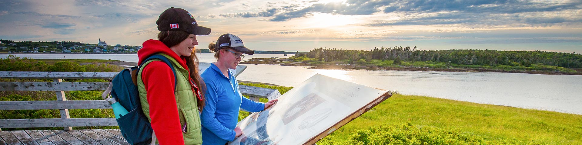 Two girls read an interpretation panel by the ocean