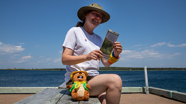A woman sits on a bench holding a brochure