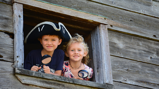 Deux enfants regardent par une fenêtre du blockhaus.  