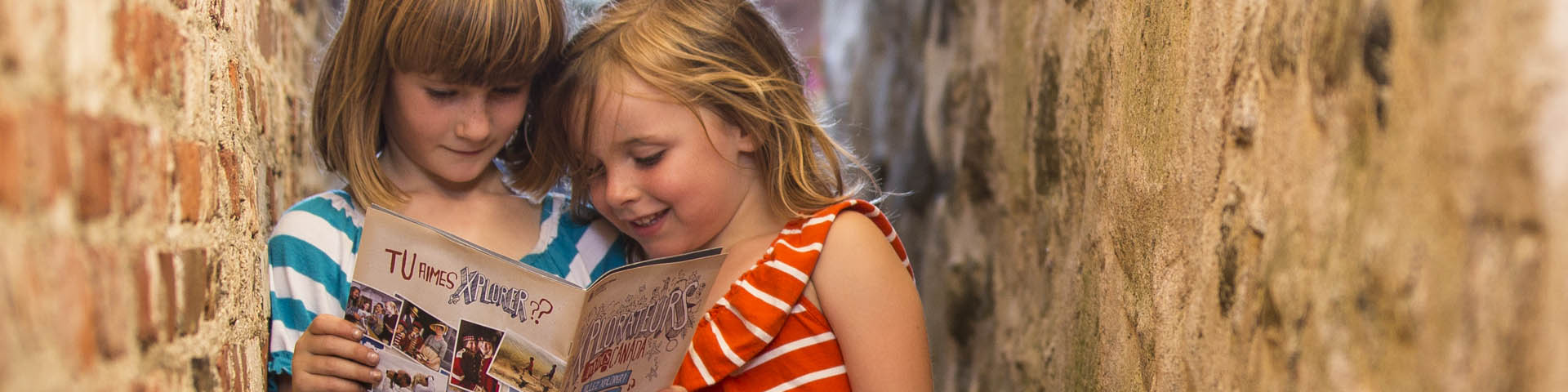 Two young visitors smiling and holding Xplorer activity booklets.