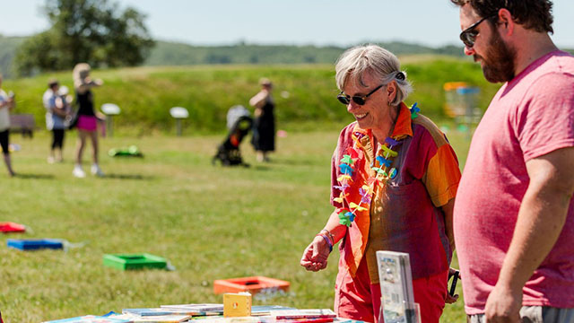 Two people dressed in colourful clothes with more people in the background.