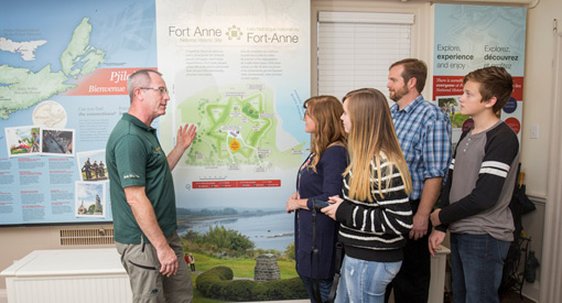 Un interprète de Parcs Canada montre une carte à un groupe de visiteurs.