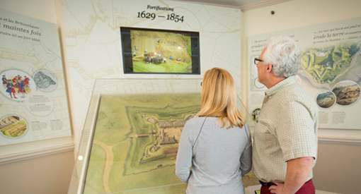 Deux visiteurs regardent une exposition sur les forts.