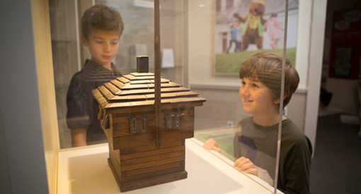 Deux enfants regardent une maquette d’un fortin sous un plexiglas.