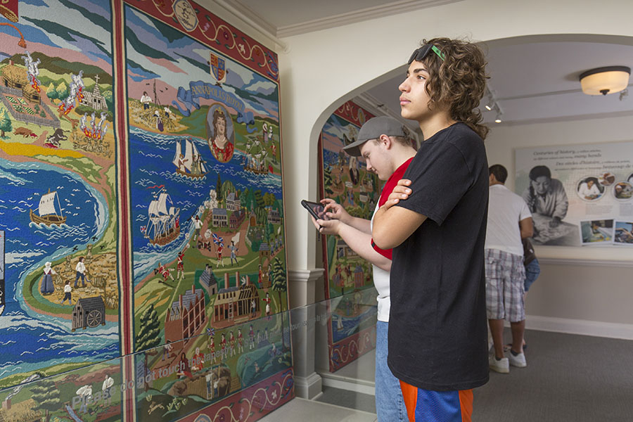 A young visitor admires the large and colourful heritage tapestry covering the wall.