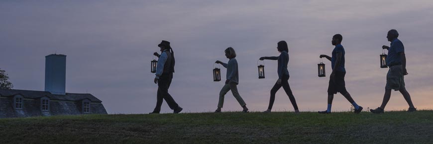 Personnes portant des lanternes au coucher du soleil.