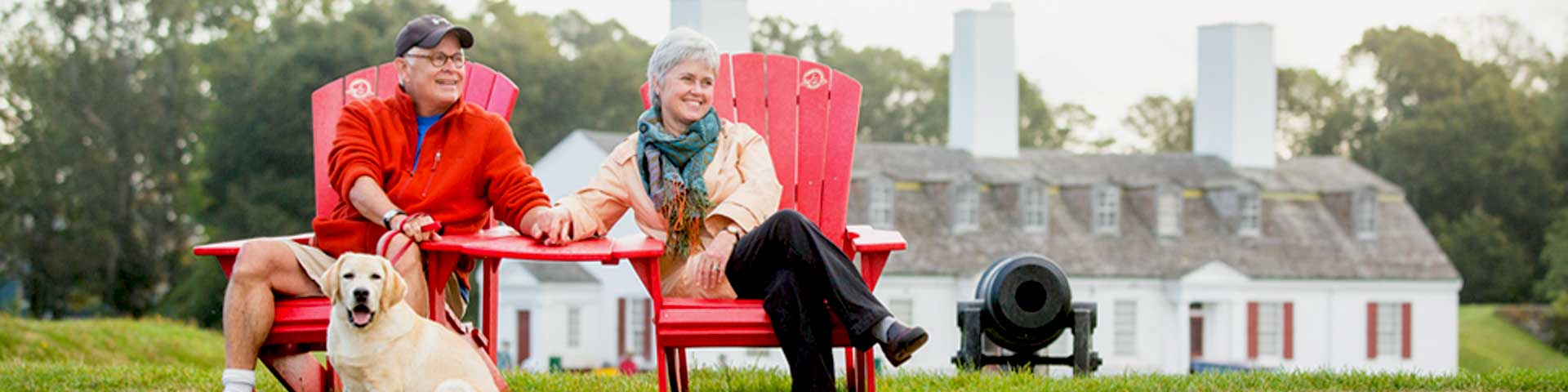 Two visitors and their dog enjoying the view from the red chairs.