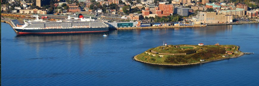 Vue aérienne de l’île Georges, de la ville d’Halifax et d’un grand bateau de croisière dans le port d’Halifax. Le bateau semble être plus gros que l’île. 