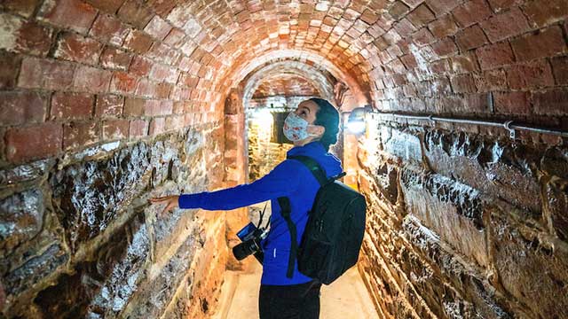 Une visiteuse explore un tunnel en briques.
