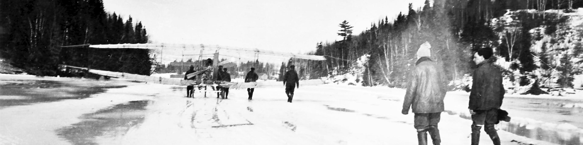 An historical photograph of a group of people with the Silver Dart on a frozen lake 