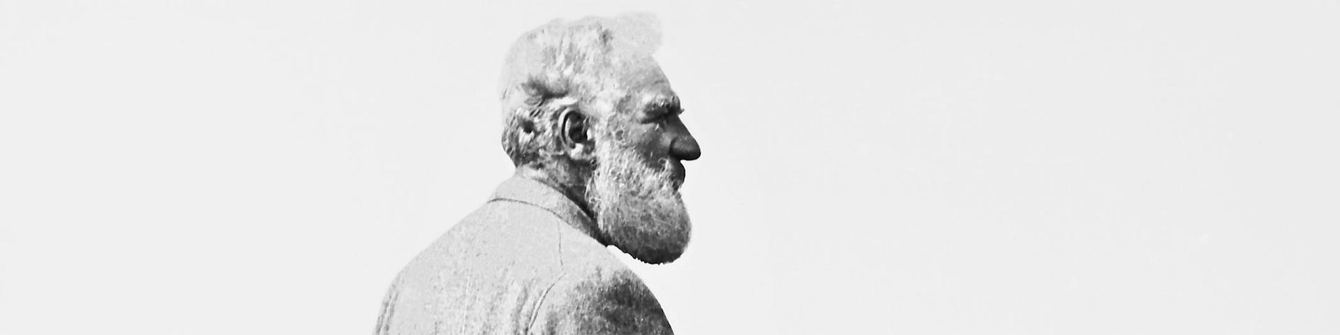 An historical photo of a side profile portrait of Alexander Graham Bell from the shoulders up. He has a long white beard,  white hair and a prominent nose.