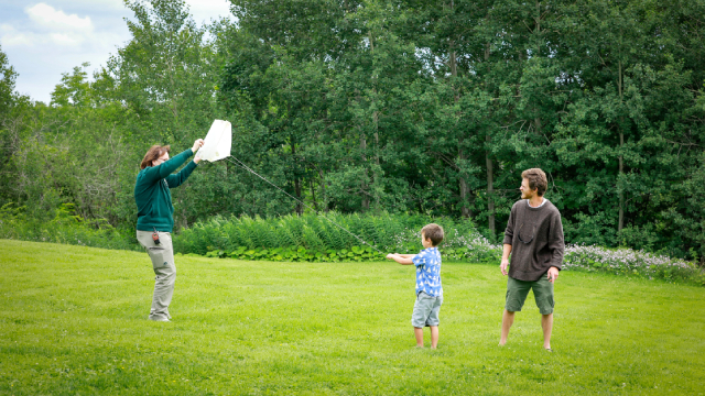An interpreter helps a little boy, and his father fly a kite.