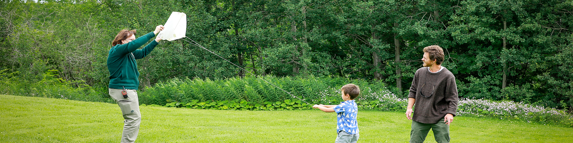 An interpreter helps a little boy, and his father fly a kite.