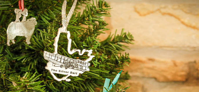 Two silver ornaments hang on a pine tree