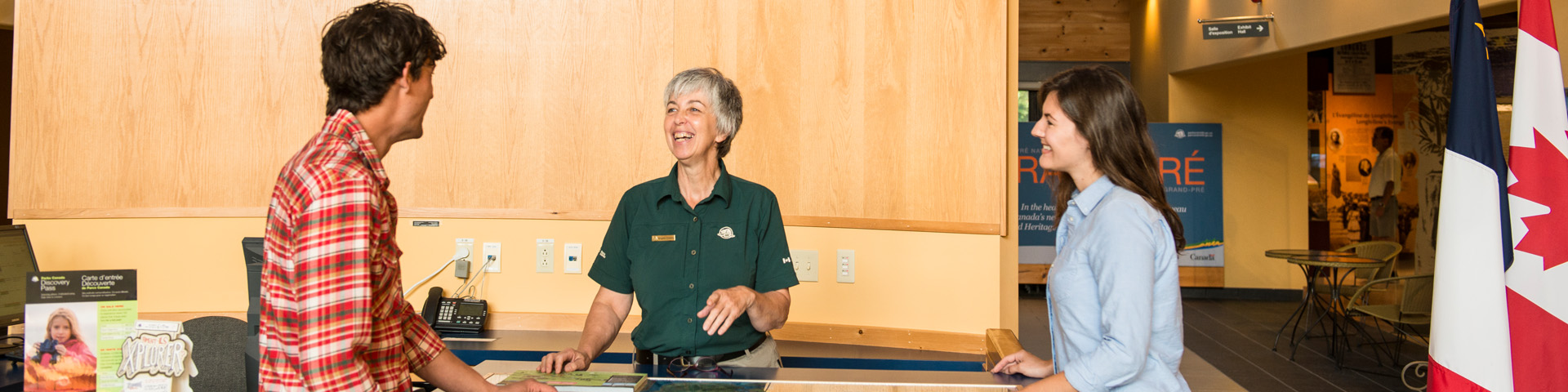 Two visitors talk to a staff member at the Visitor Information Centre's front desk