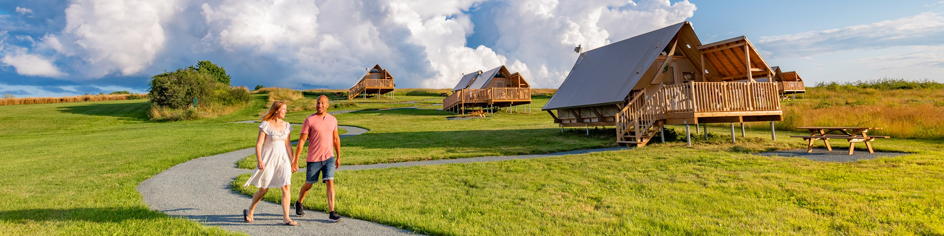 Un couple marche main dans la main sur un sentier de gravier près des oTENTiks à Grand-Pré.