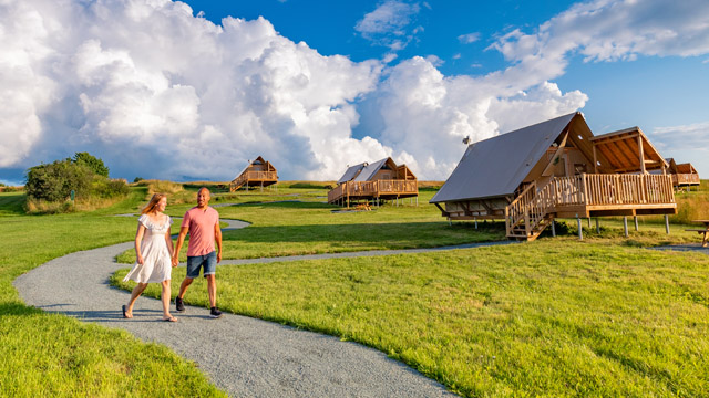 A couple walking hand in hand on a gravel walking path near the oTENTiks in Grand-Pré