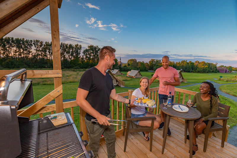 A group of friends enjoing a BBQ on the deck of their oTENTik at Grand-Pré.