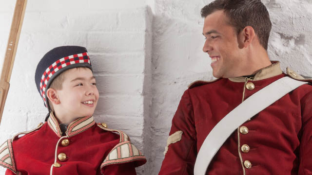 A young boy and interpreter dressed in 78th Highlander uniforms sharing a conversation at Halifax Citadel National Historic Site.