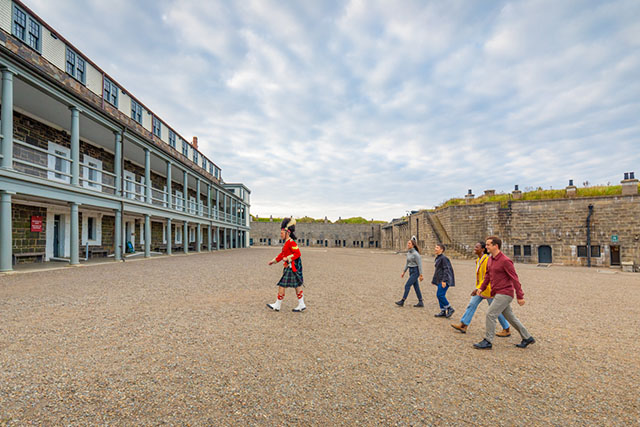 Les visiteurs suivent un interprète historique à travers le terrain de rassemblement jusqu’au bâtiment.
