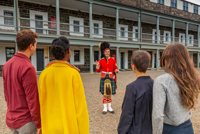 Les visiteurs écoutent un interprète historique à l’extérieur du bâtiment.
