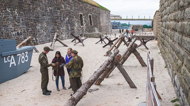 Deux visiteurs et deux soldats sont entourés de barricades de l’exposition.