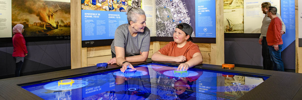 Visitors lean over to interact with a digital exhibit.